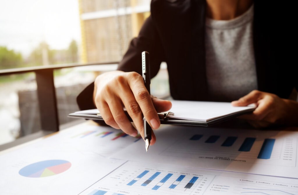 Contador em mesa de trabalho segura caneta e prancheta com gráficos e análises, representando a importância de escolher os melhores escritórios de contabilidade de SP.